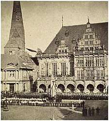 Abbildung: Eine Frühfotografie von Rathaus und Roland aus der Bildsammlung. Ein Festaufzug auf dem Markt am 18. Oktober 1865